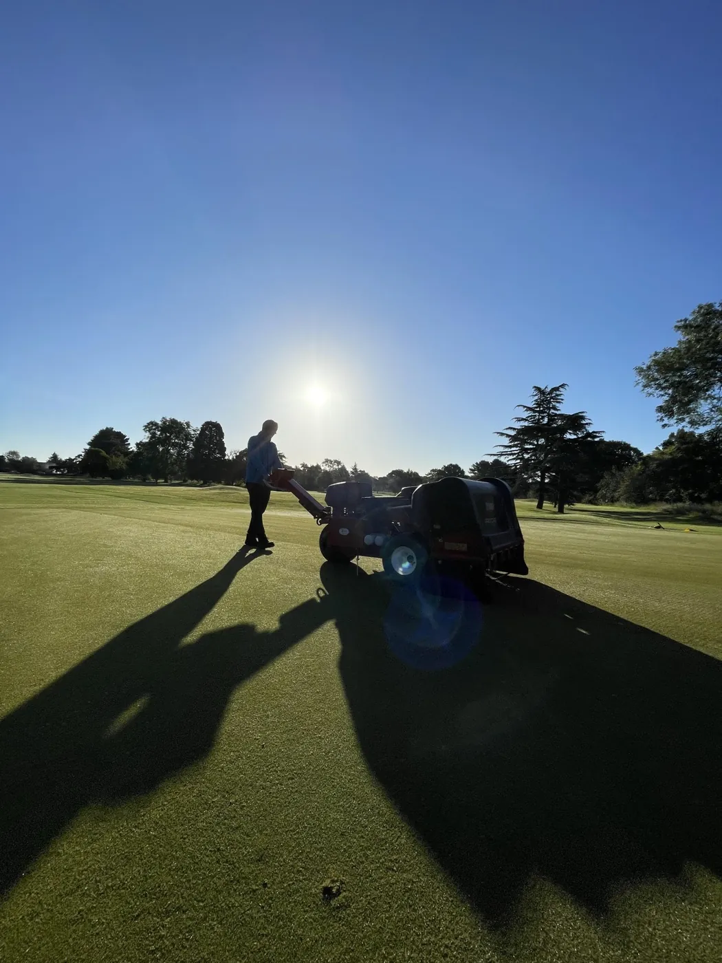Greenkeeper preparing the greens at sunrise